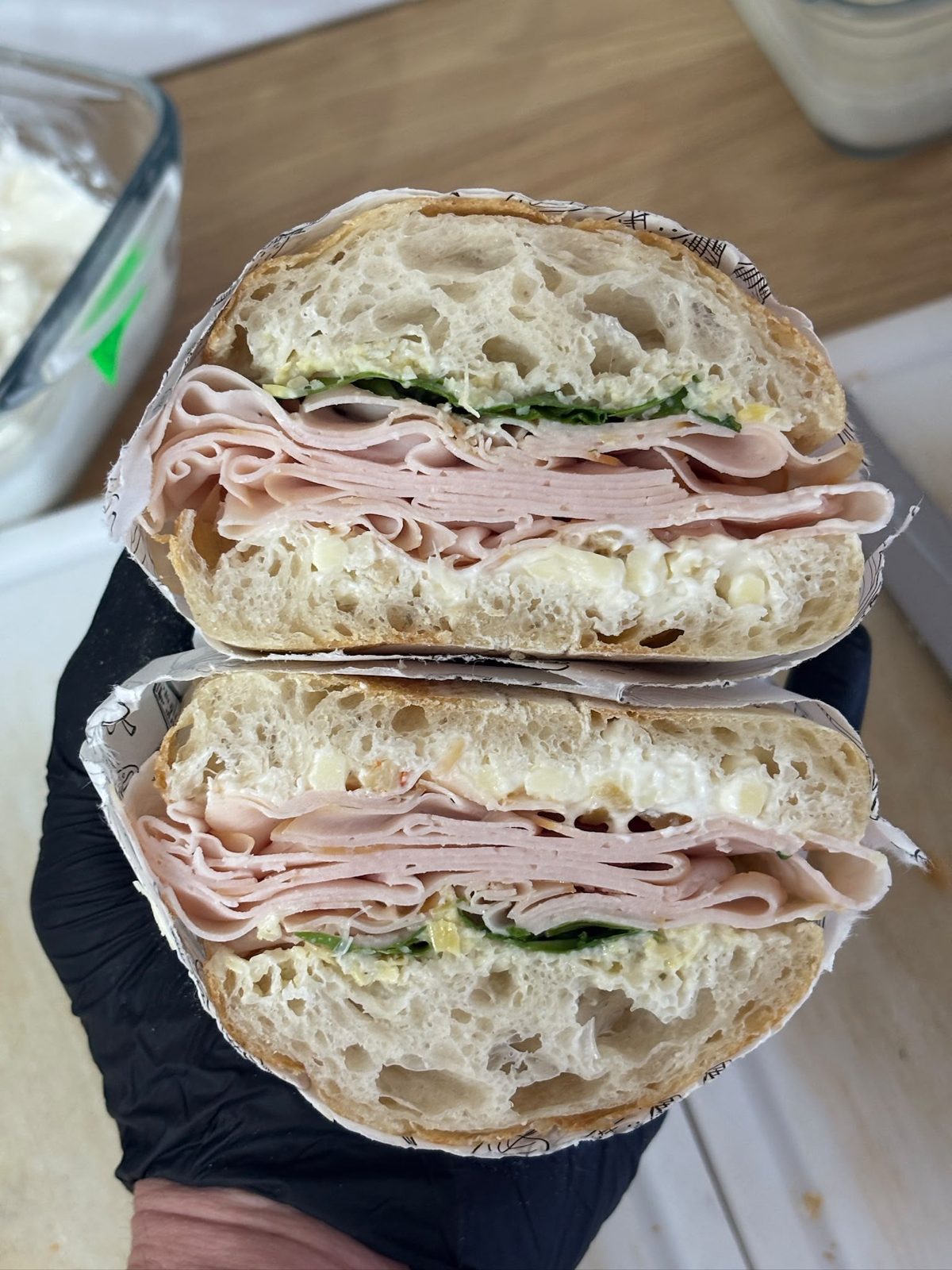 Panino cu prosciutto cotto, tăiat în două, ținut în mână